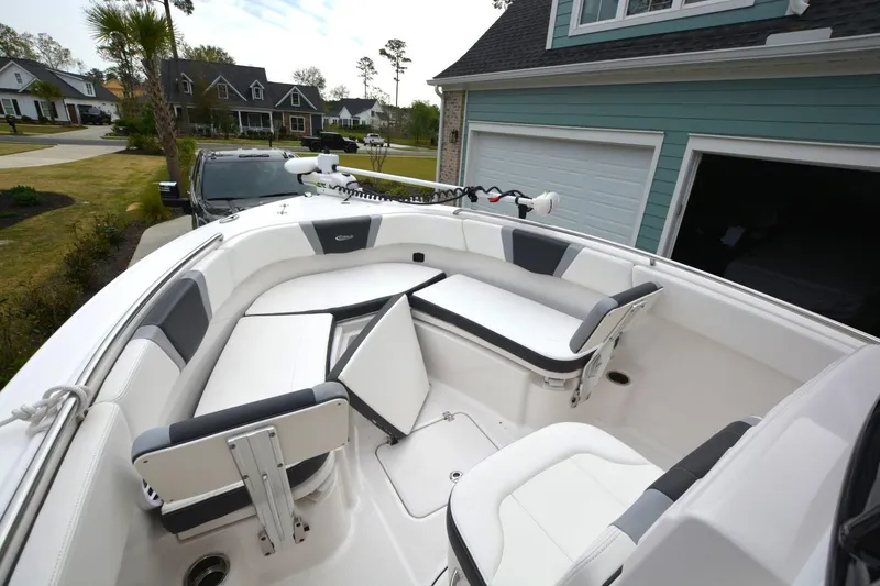 Slide: The Image of 2023 Robalo R230 Center Console boat with spacious seating, parked near a house. - 6
