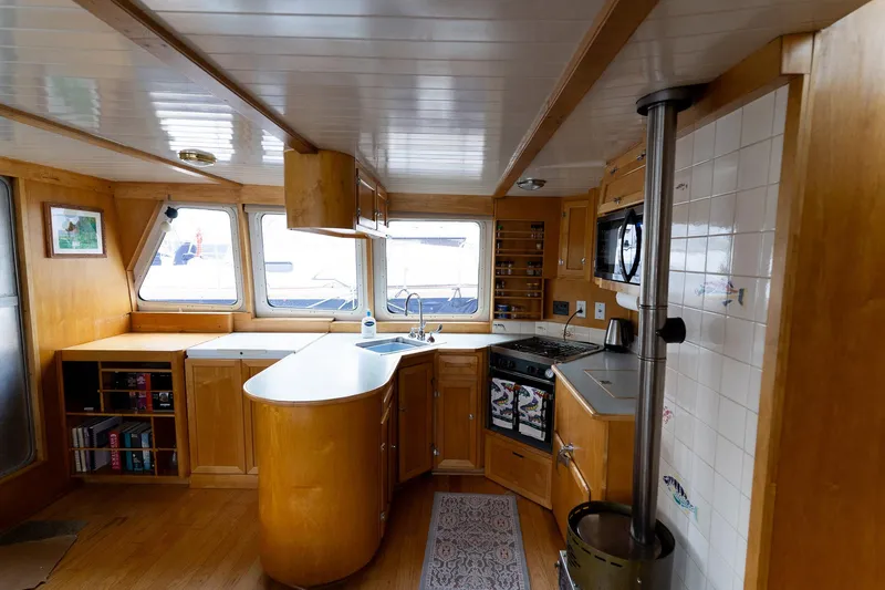 Slide: The Image of Interior of a 1997 Custom Steel Trawler with a cozy wooden kitchen and nautical decor. - 18