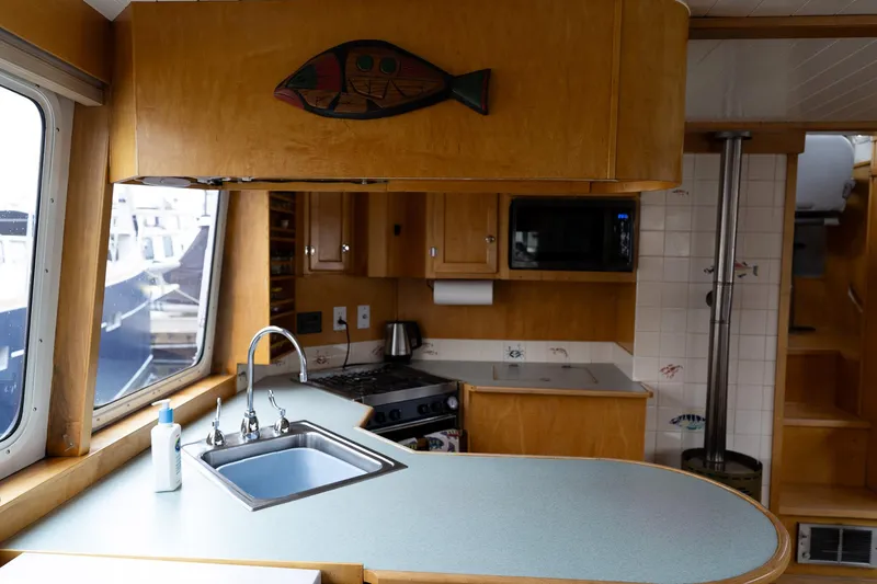 Slide: The Image of Interior of a 1997 Custom Steel Trawler kitchen with wooden cabinetry and modern appliances. - 19