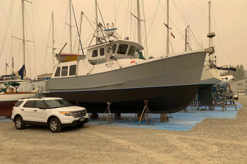 Slide: The Image of Custom 1997 Steel Trawler on dry dock beside a white SUV, surrounded by sailboats. - 2