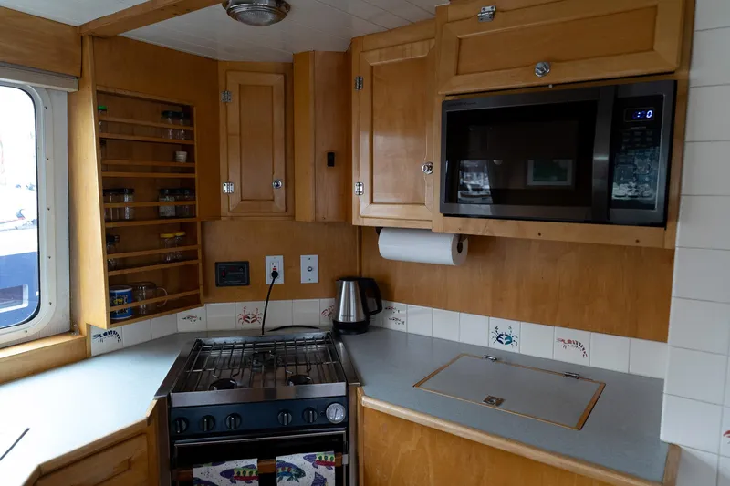 Slide: The Image of Cozy kitchen in a 1997 Custom Steel Trawler with wooden cabinets and modern appliances. - 20