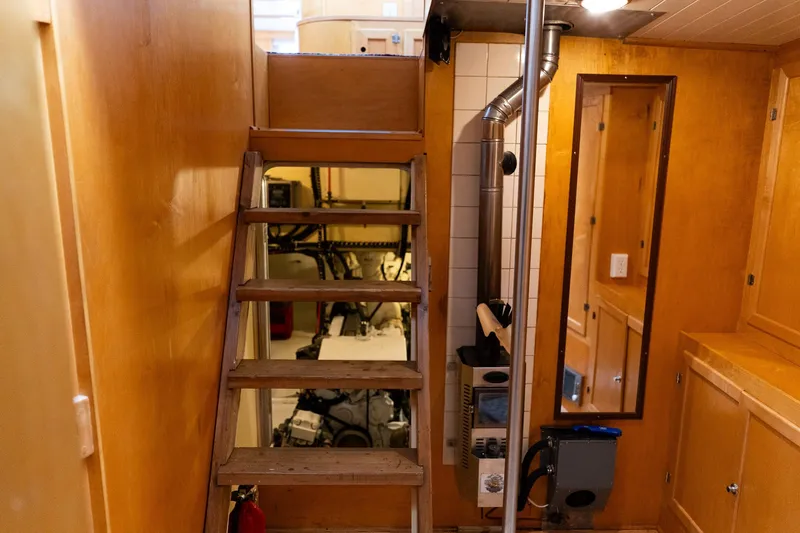 Slide: The Image of Interior of a 1997 Custom Steel Trawler with wooden stairs and visible engine room. - 22