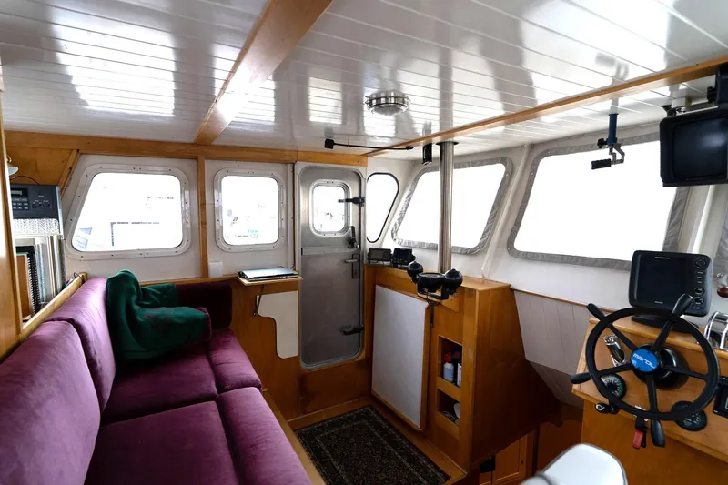 Slide: The Image of Interior of a 1997 Custom Steel Trawler with purple seating and navigation equipment. - 24
