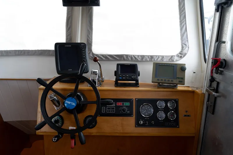 Slide: The Image of Control panel of a 1997 Custom Steel Trawler with navigation instruments and steering wheel. - 27