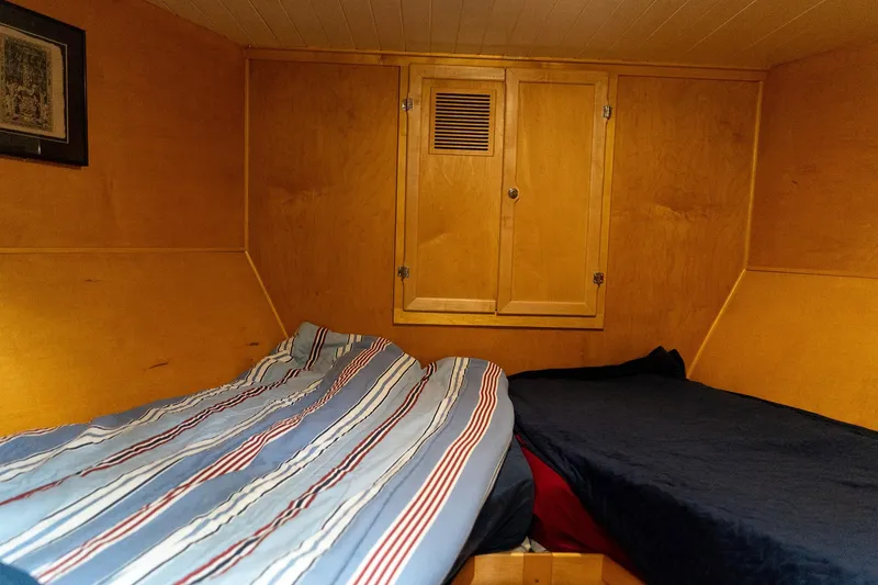Slide: The Image of Cozy cabin interior of a 1997 Custom Steel Trawler with twin beds and wooden paneling. - 31