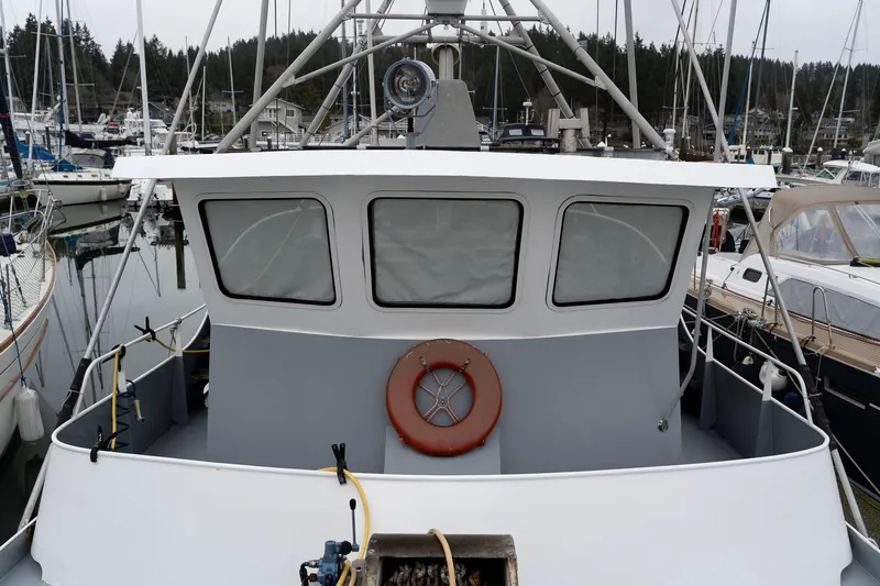 Slide: The Image of Custom 1997 Steel Trawler docked in marina, featuring a lifebuoy and multiple windows. - 34
