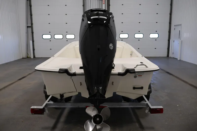 Slide: The Image of 2022 Mako Pro Skiff 17 CC boat in a garage, rear view with outboard motor. - 5