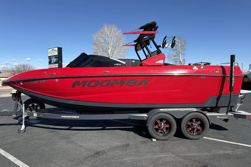 Slide: The Image of Red 2022 Moomba Mojo boat on trailer, parked outdoors under clear blue sky. - 2