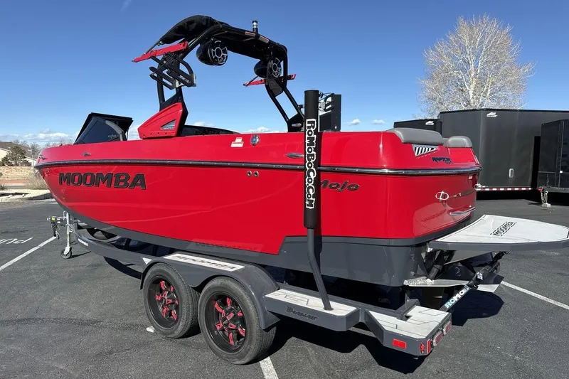 Slide: The Image of 2022 Moomba Mojo boat in vibrant red, parked on a trailer under a clear blue sky. - 3