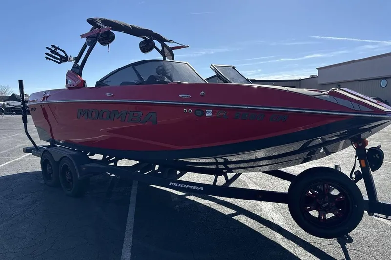 Slide: The Image of 2022 Moomba Mojo boat in red on a trailer, parked outdoors. - 7