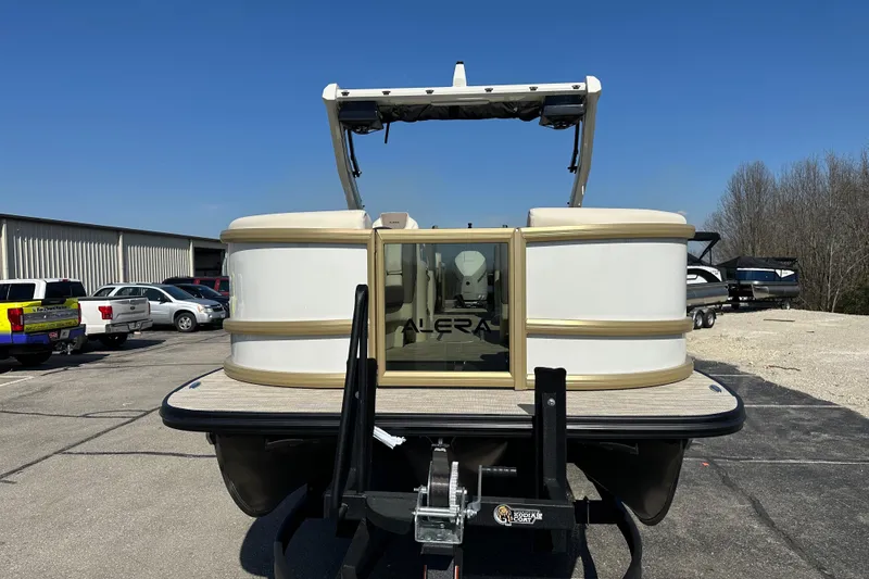Slide: The Image of Front view of 2026 Alera M23Q pontoon boat on trailer in parking lot. - 2