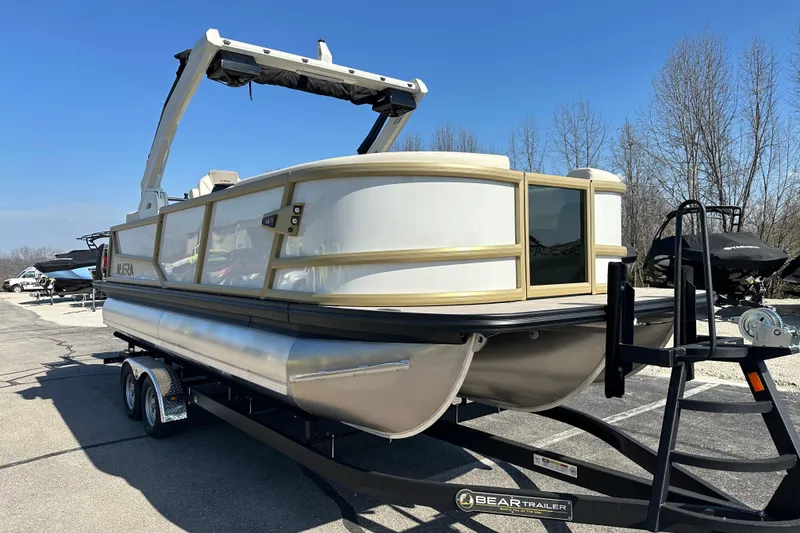 Slide: The Image of 2026 Alera M23Q pontoon boat on trailer, parked outdoors under clear blue sky. - 7