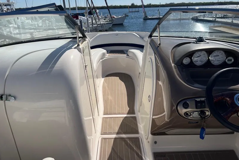 Slide: The Image of 2005 Regal 2400 Bowrider boat interior with dashboard and seating, docked by the water. - 10