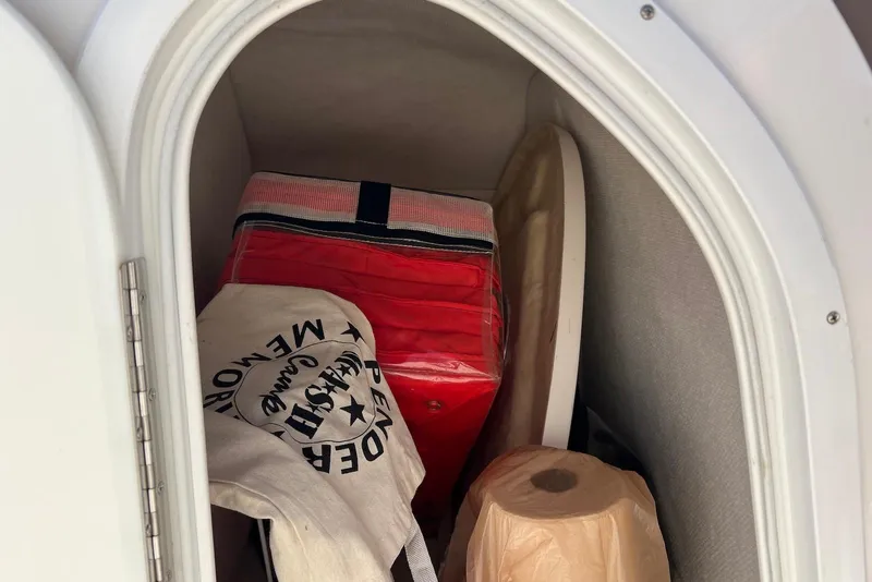 Slide: The Image of Storage compartment in a 2005 Regal 2400 Bowrider boat with various items. - 34