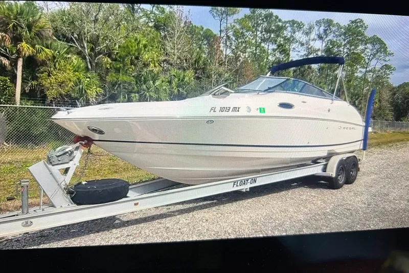 Slide: The Image of 2005 Regal 2400 Bowrider on trailer, parked outdoors with lush greenery background. - 39