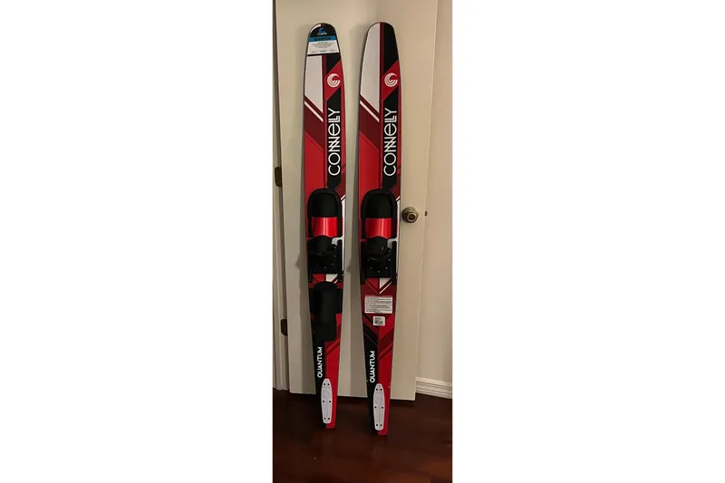 Slide: The Image of Pair of Connelly water skis with red and black design, leaning against a wall. - 42