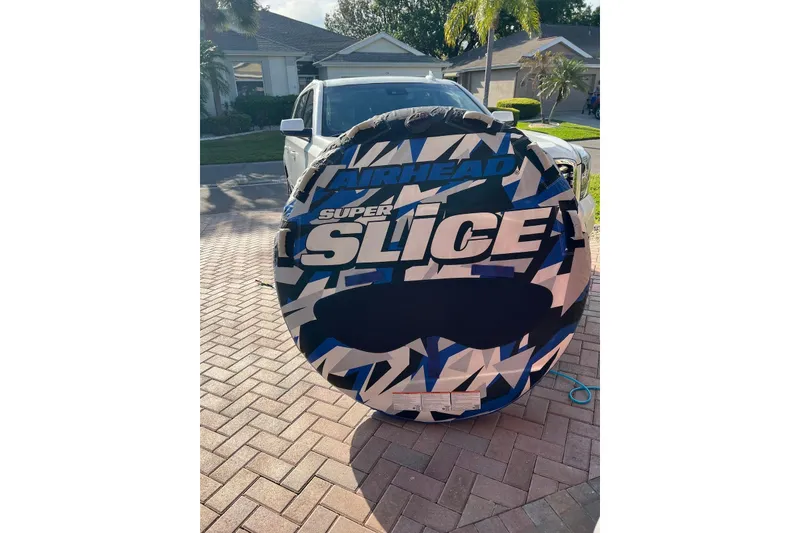 Slide: The Image of Airhead Super Slice inflatable tube on driveway, with a 2005 Regal 2400 Bowrider in the background. - 43