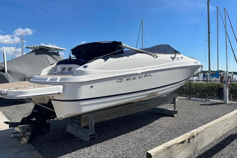 Slide: The Image of 2005 Regal 2400 Bowrider boat on display at a marina under clear blue skies. - 5