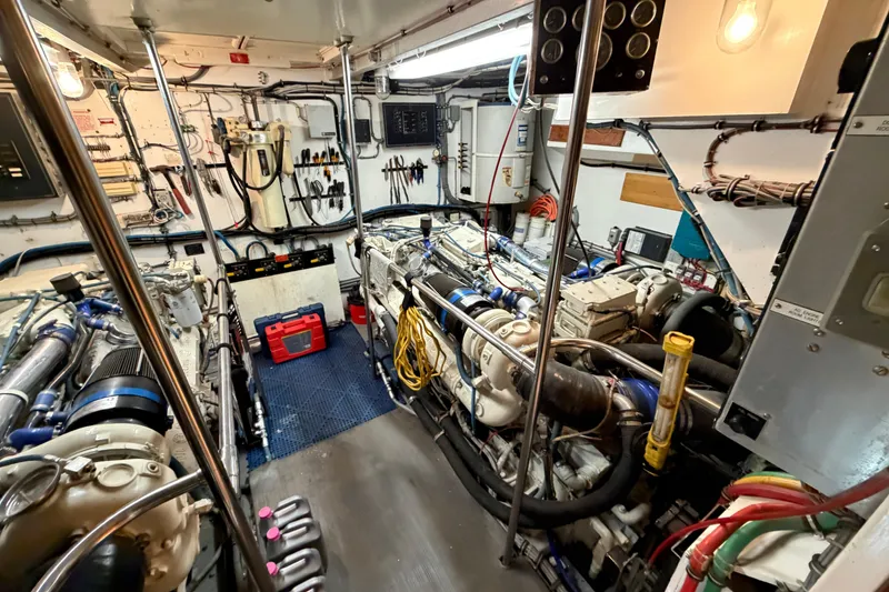 Slide: The Image of Engine room of a 1991 Hatteras 70 Motor Yacht, featuring dual engines and maintenance tools. - 111