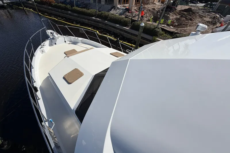 Slide: The Image of 1991 Hatteras 70 Motor Yacht with chrome horns, docked near luxury waterfront homes. - 12