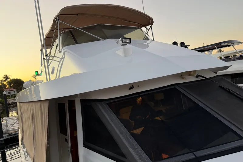 Slide: The Image of 1991 Hatteras 70 Motor Yacht docked at sunset, featuring covered seating and sleek design. - 25