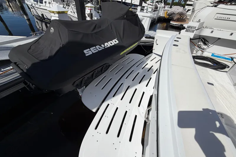 Slide: The Image of 1991 Hatteras 70 Motor Yacht docked with covered jet ski, palm trees in background. - 30