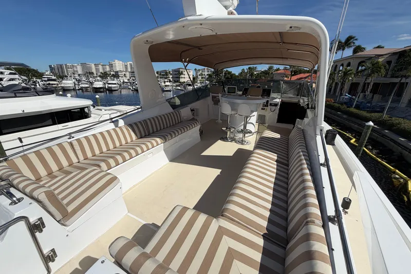 Slide: The Image of 1991 Hatteras 70 Motor Yacht deck with striped seating, docked at marina. - 48