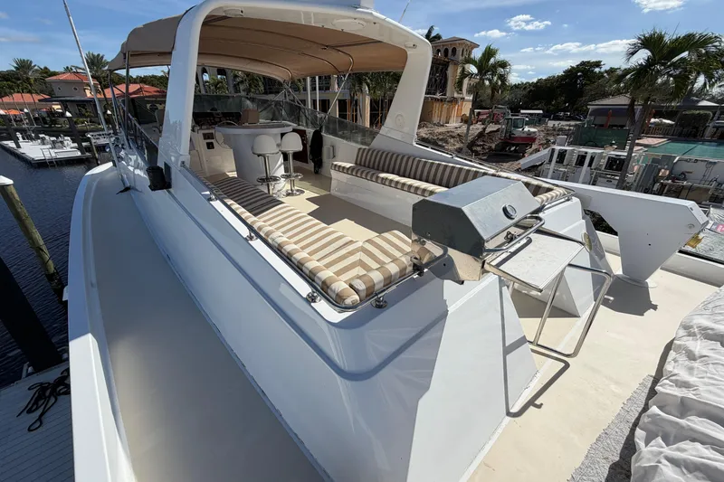 Slide: The Image of 1991 Hatteras 70 Motor Yacht with striped seating and helm, docked in marina. - 49