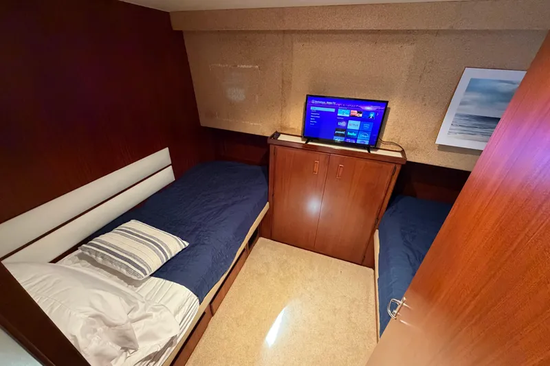 Slide: The Image of 1991 Hatteras 70 Motor Yacht cabin with cozy bed and modern TV setup. - 85
