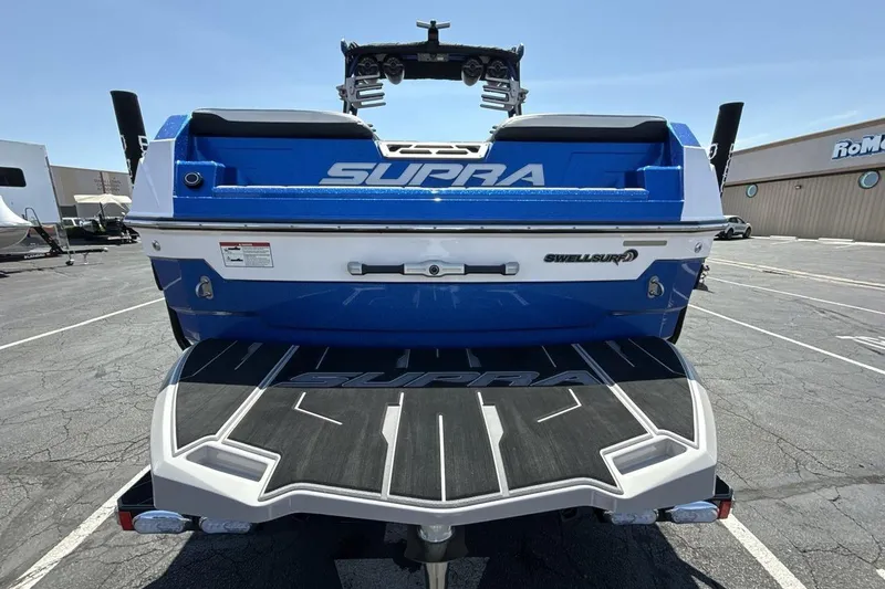 Slide: The Image of 2023 Supra SE 550 boat rear view, featuring SwellSurf technology, in a parking lot. - 4