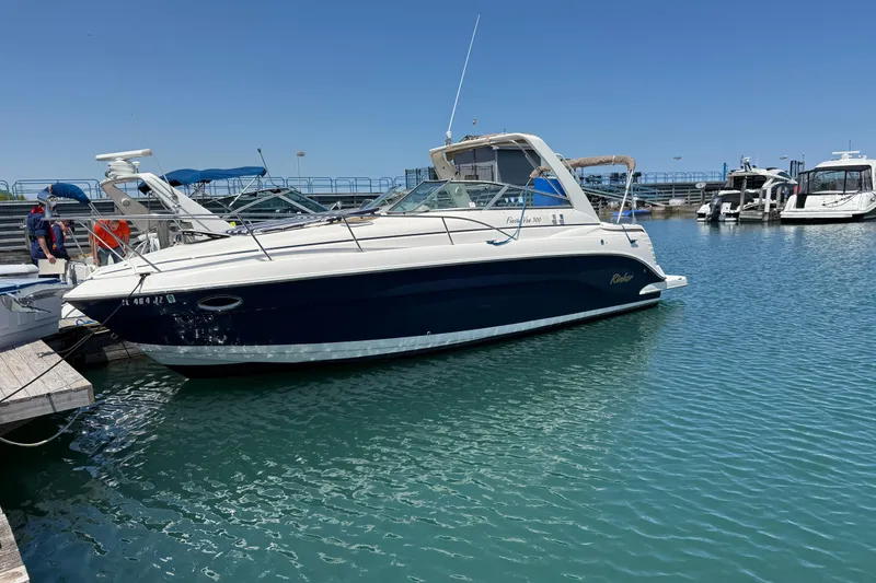 The Image of 2005 Rinker Fiesta Vee 300 boat docked in a marina under clear blue skies. - 0