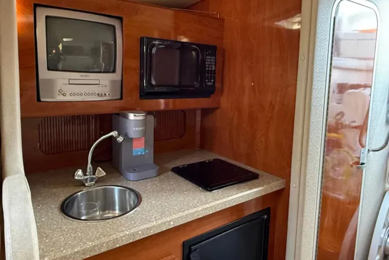 Slide: The Image of 2005 Rinker Fiesta Vee 300 kitchenette with sink, microwave, and TV. - 12