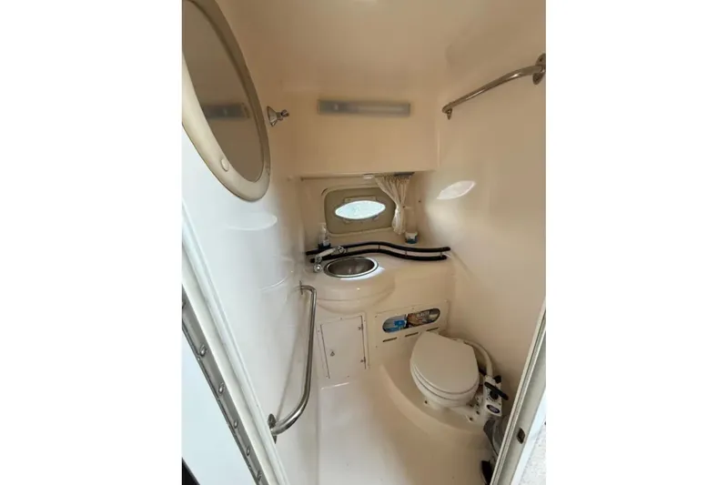Slide: The Image of 2005 Rinker Fiesta Vee 300 boat bathroom with sink, toilet, and porthole window. - 14