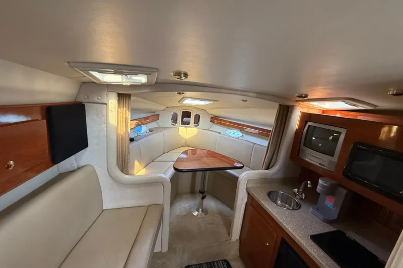 Slide: The Image of 2005 Rinker Fiesta Vee 300 cabin interior with seating, kitchenette, and wood accents. - 3