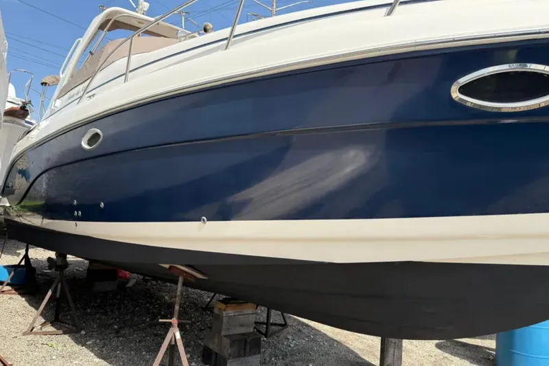 Slide: The Image of 2005 Rinker Fiesta Vee 300 boat on stands, blue and white hull. - 4