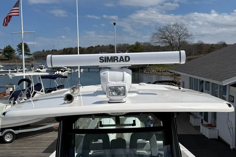 Slide: The Image of 2026 Boston Whaler 330 Outrage with Simrad radar, docked at marina under blue sky. - 13