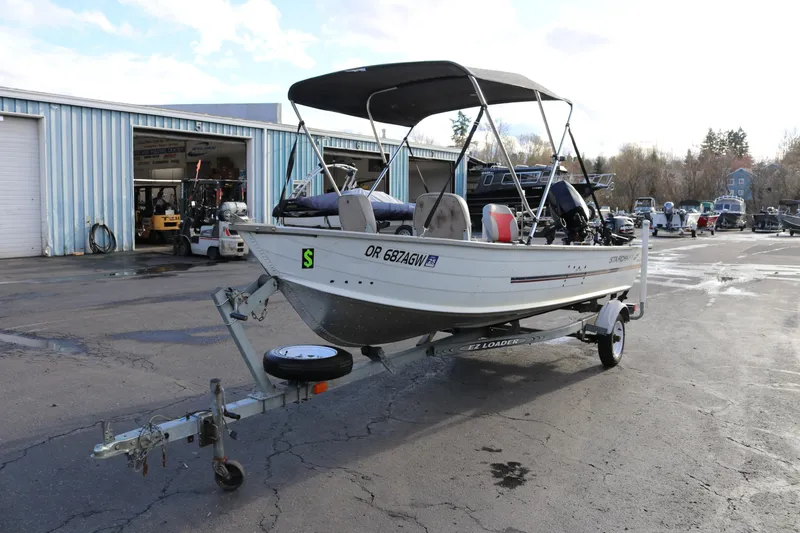 Slide: The Image of 1997 Starcraft Patriot 160 boat on trailer outside a garage. - 4
