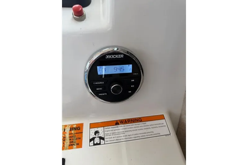 Slide: The Image of Kicker stereo system on 2015 Parker 2520XLD boat dashboard with warning label. - 13