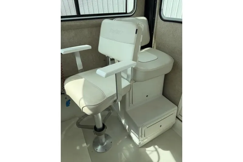 Slide: The Image of Captain's chair inside 2015 Parker 2520XLD boat, featuring white upholstery and armrests. - 15