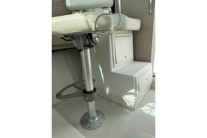 Slide: The Image of Interior view of a 2015 Parker 2520XLD boat, featuring a cushioned seat and storage compartment. - 20