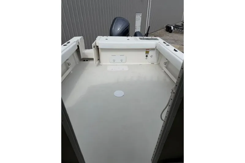 Slide: The Image of 2015 Parker 2520XLD boat deck with outboard motor, docked near a metal building. - 22