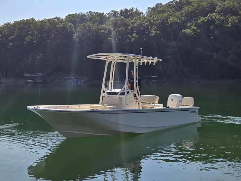 Slide: The Image of A 2026 Boston Whaler 190 Montauk on calm water, surrounded by wooded shores. - 17