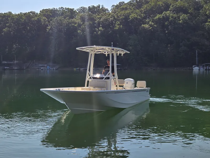 Slide: The Image of A 2026 Boston Whaler 190 Montauk cruising on a calm lake with a wooded shoreline. - 1