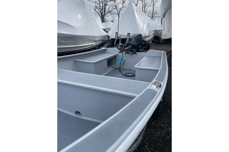 Slide: The Image of 2026 Holland 14 boat with motor, parked outdoors, covered boats in background. - 4