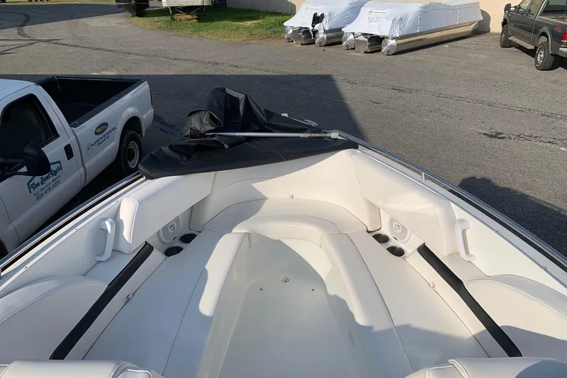 Slide: The Image of 2004 Formula 260 Bowrider boat with white seating, parked near trucks and covered boats. - 7