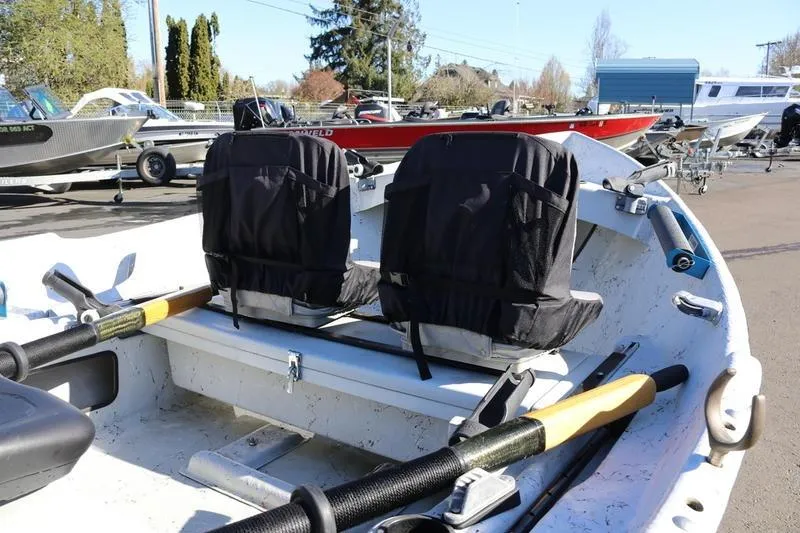 The Image of 2005 ClackaCraft 16 Drift Boat with oars and seating, parked among other boats. - 1