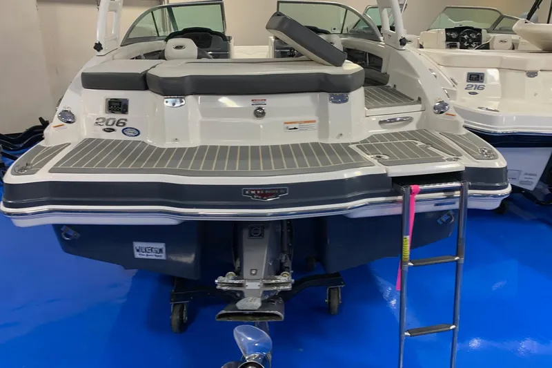 Slide: The Image of 2014 Chaparral 206 SSi boat with swim platform and ladder, displayed indoors. - 2