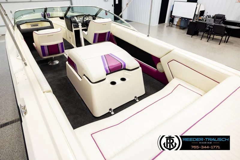 Slide: The Image of 1993 American Skier Eagle boat interior with white and purple seating, showcased in a showroom. - 10