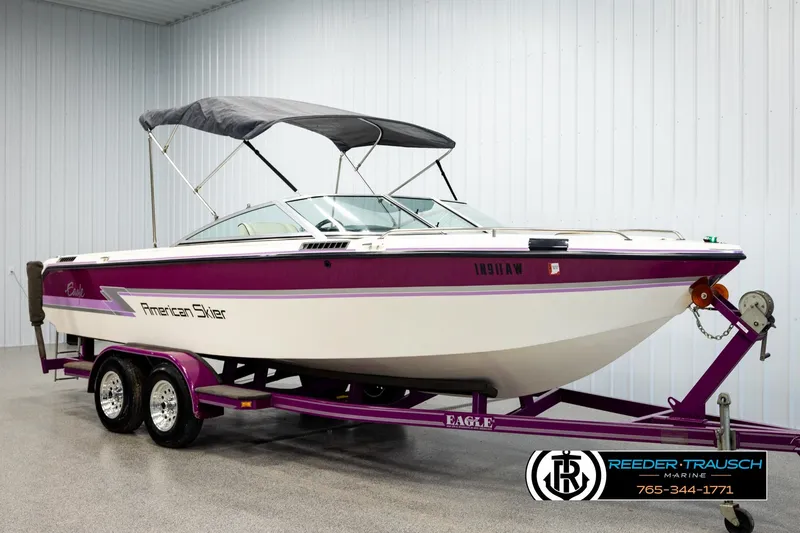 Slide: The Image of 1993 American Skier Eagle boat with purple accents on a matching trailer in a showroom. - 3