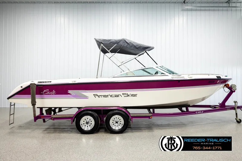 Slide: The Image of 1993 American Skier Eagle boat with purple accents on a trailer in a showroom. - 4